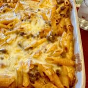 Layered pasta with beef, sauce and melted cheese in a baking dish.