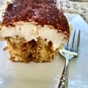 A serving of tiramisu cake on a plate with a fork.