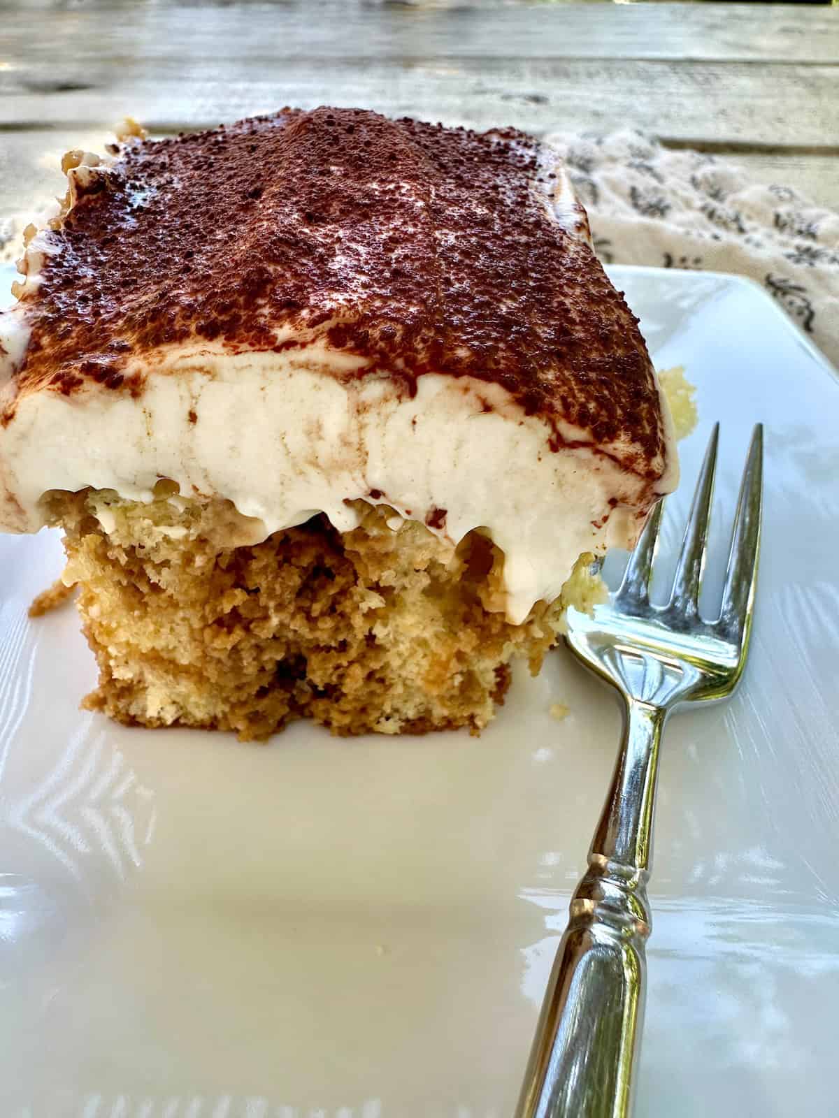 A serving of tiramisu cake on a plate with a fork.