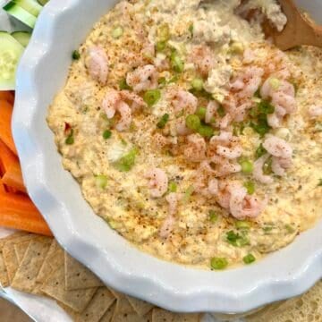 Shrimp and crab dip on a serving platter with crackers and vegetables.