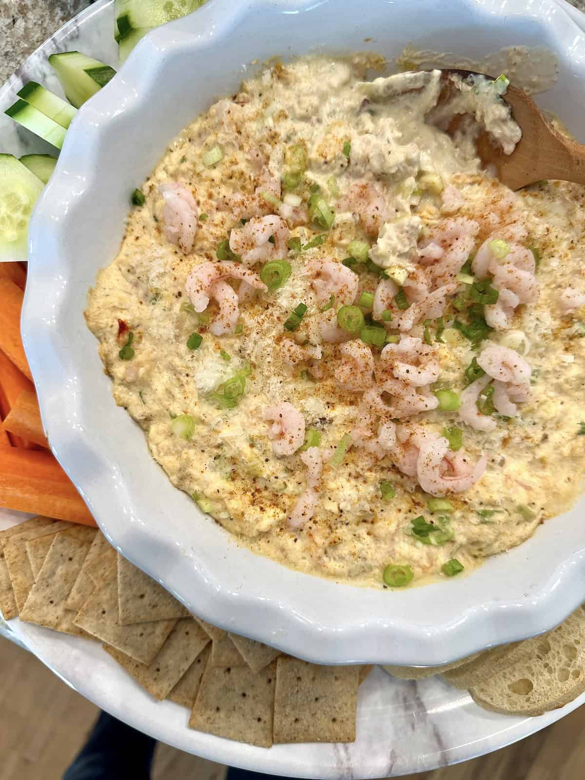 Shrimp and crab dip on a serving platter with crackers and vegetables.
