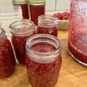 Easy small batch raspberry jam in jars on a cutting board.