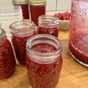 Easy small batch raspberry jam in jars on a cutting board.