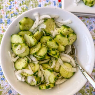 A serving bowl of sliced cucumbers and onions.