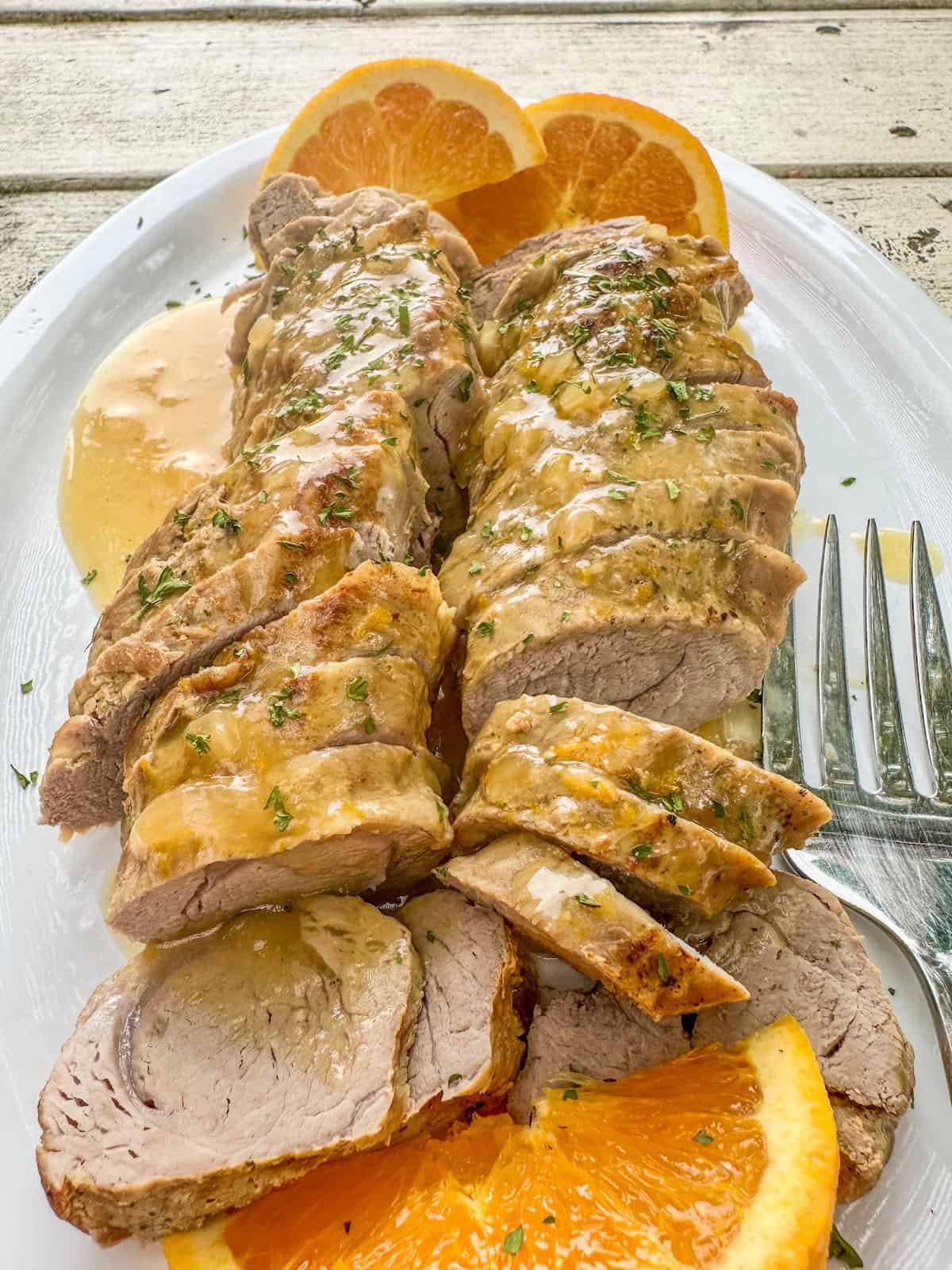 Boneless pork tenderloin slices with orange glaze and sliced oranges.