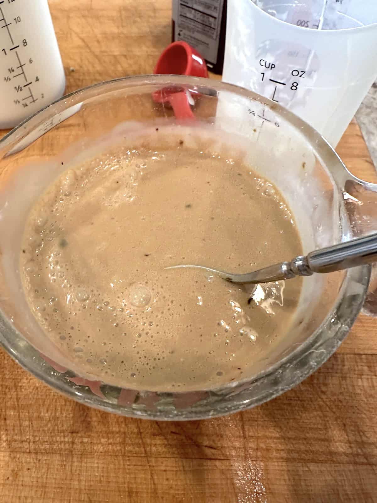 Coffee and sweeteners in a glass measuring cup.