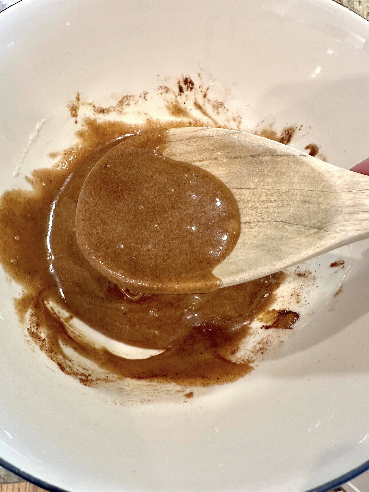 Blended spiced walnuts ingredients in a bowl with a wooden spoon.
