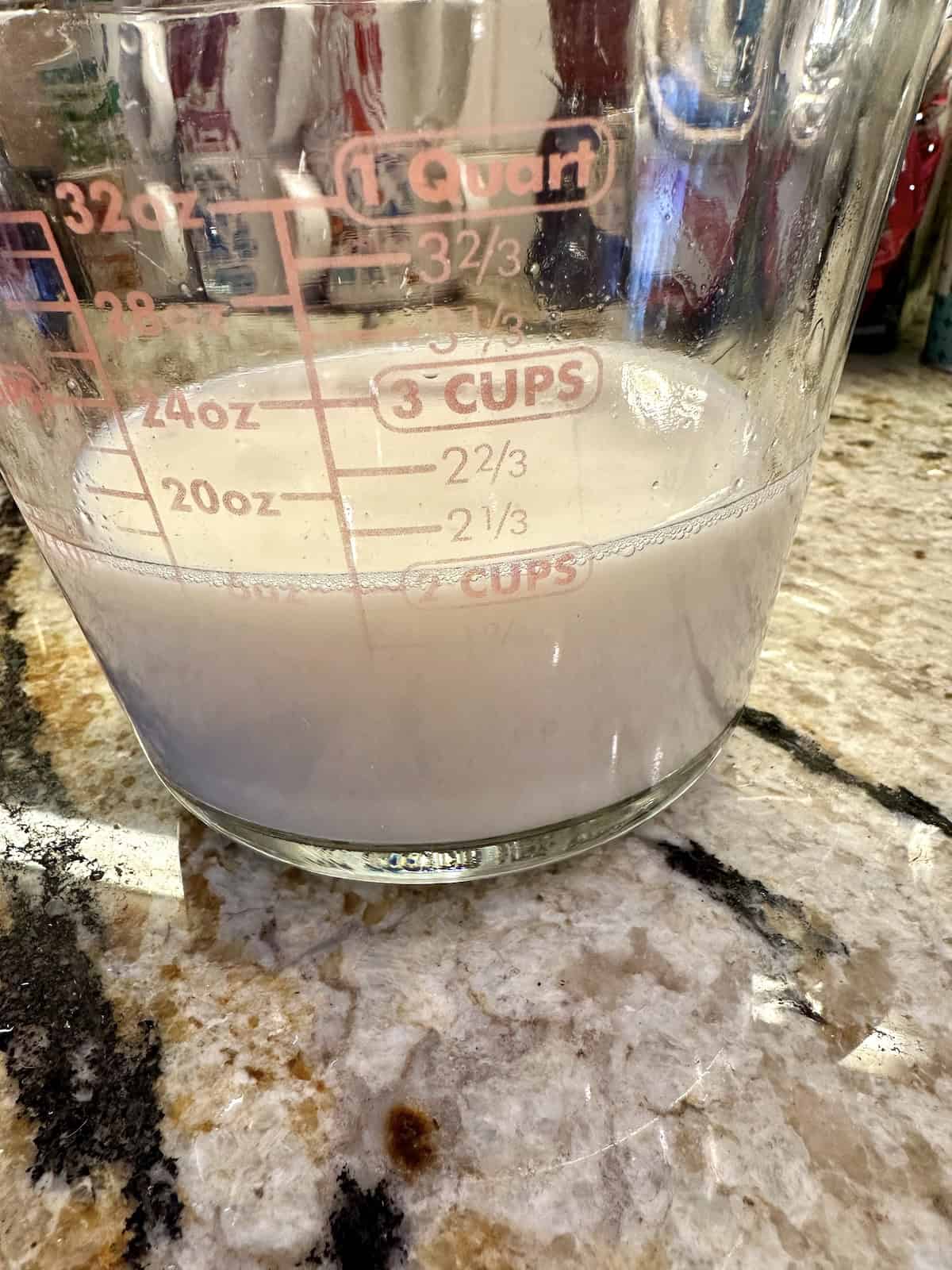Canned clam juice with milk in a measuring cup.