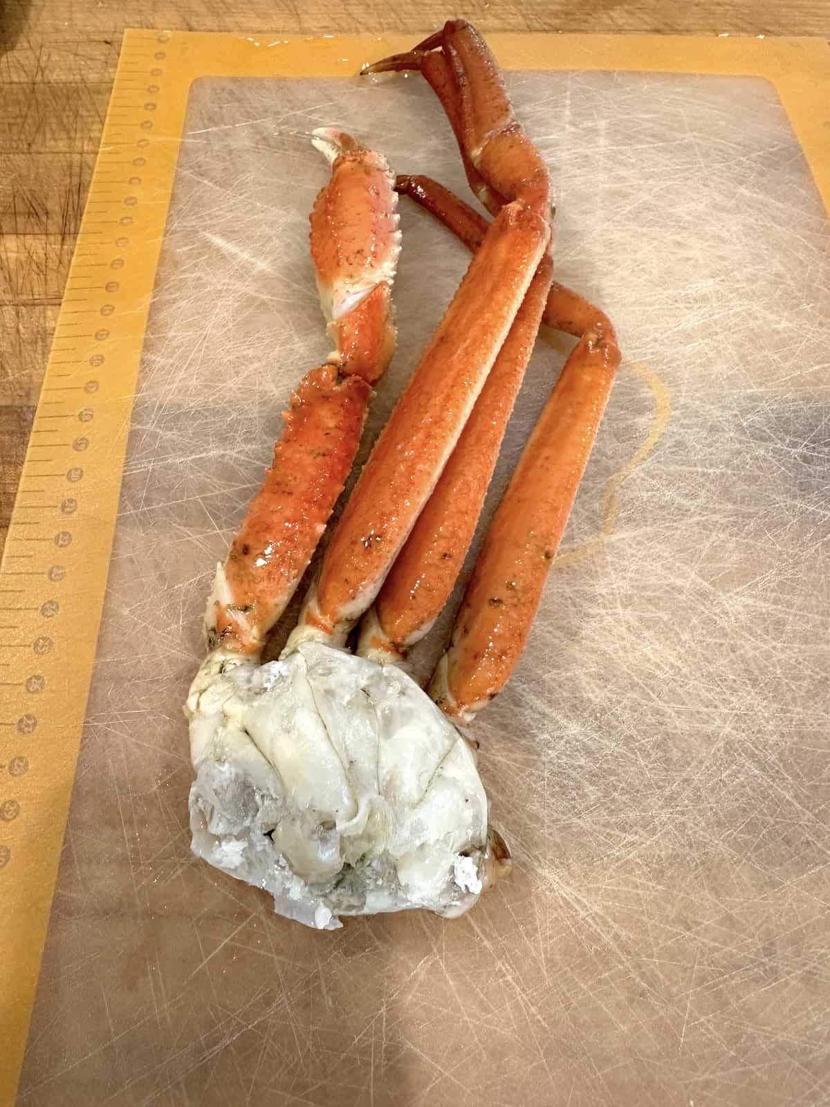 Two crab legs on a cutting board.