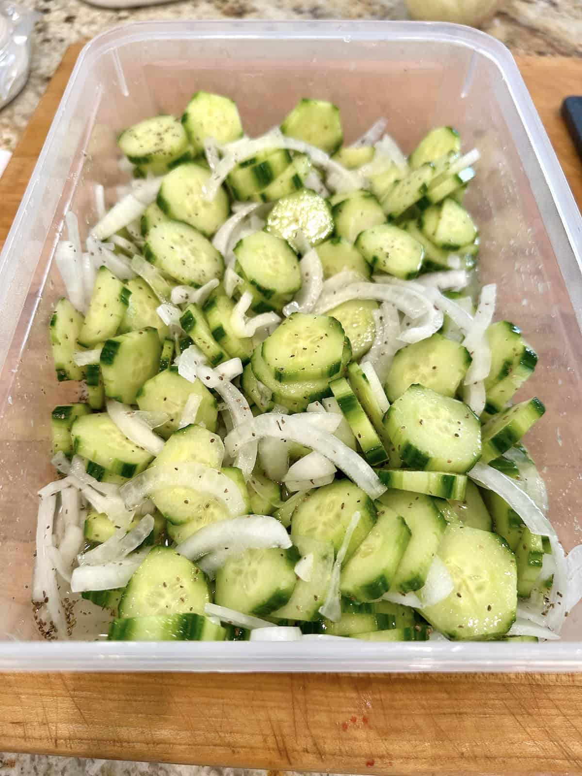 Quick pickled cucumbers and onions in a container with brine added.