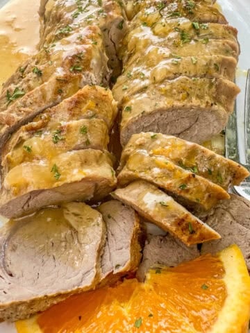 Sliced, boneless pork tenderloin with orange sauce and sliced oranges.