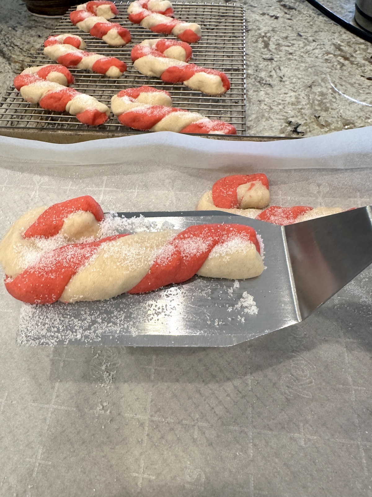 A spatula lifts a Christmas cookie from a baking sheet.