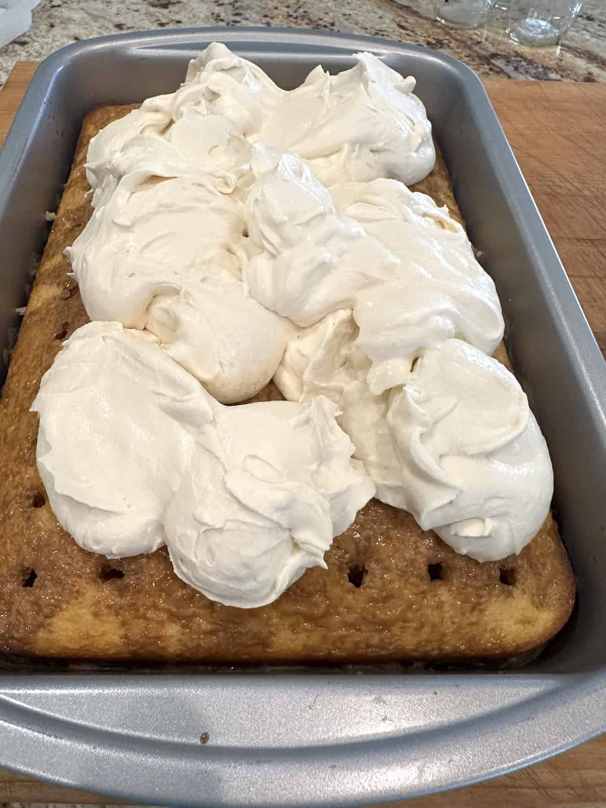 Mounds of mascarpone frosting on top of a baked tiramisu cake.