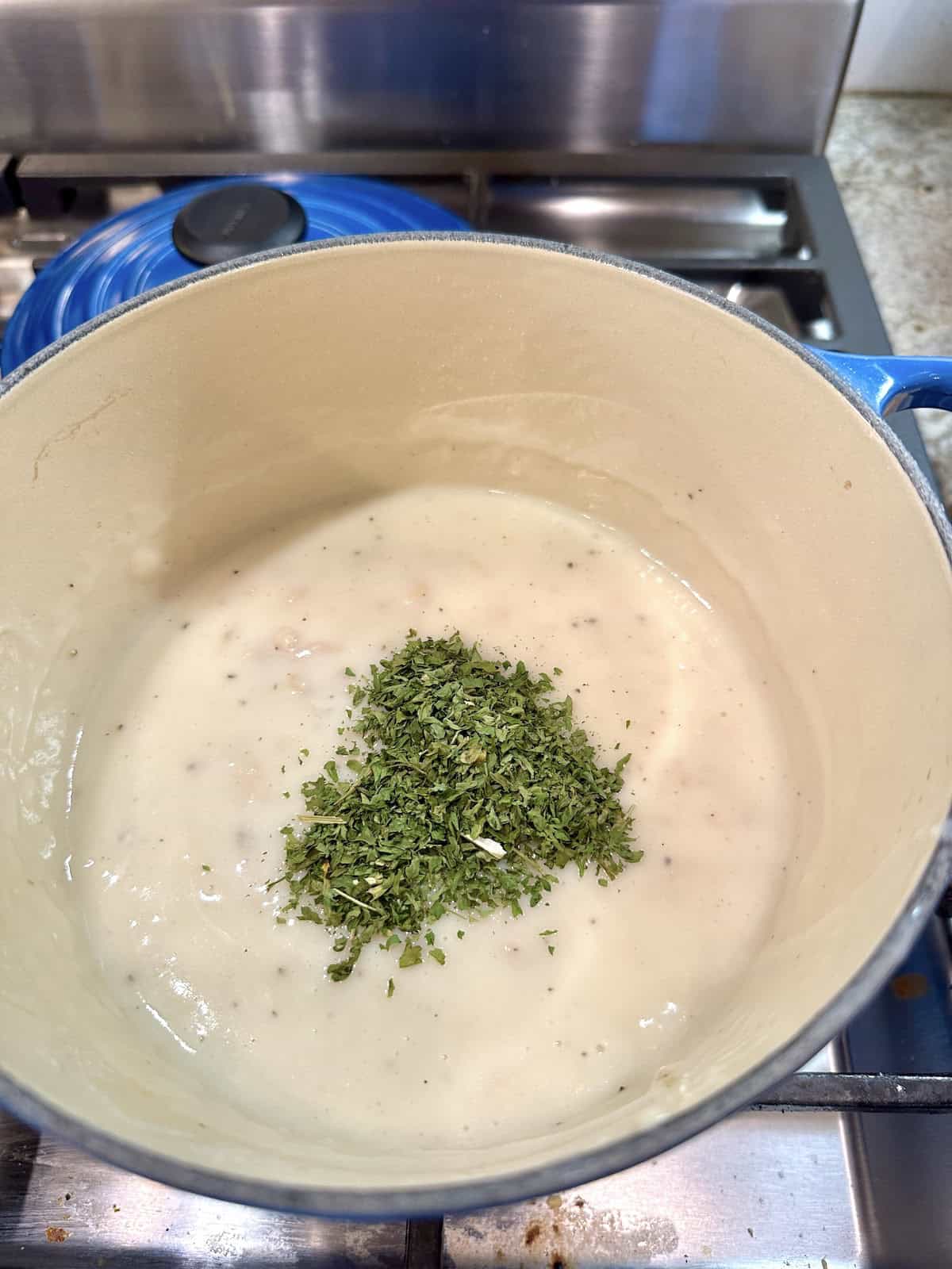 Parsley on white clam sauce in a pan.