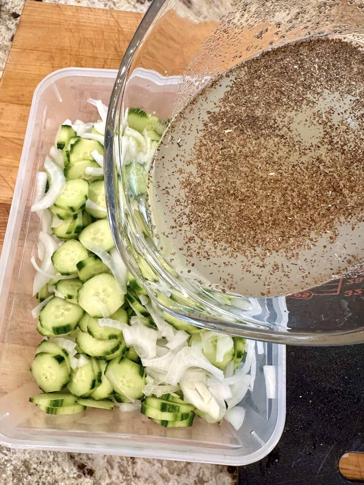 Pouring brine over cucumber and onion slices.