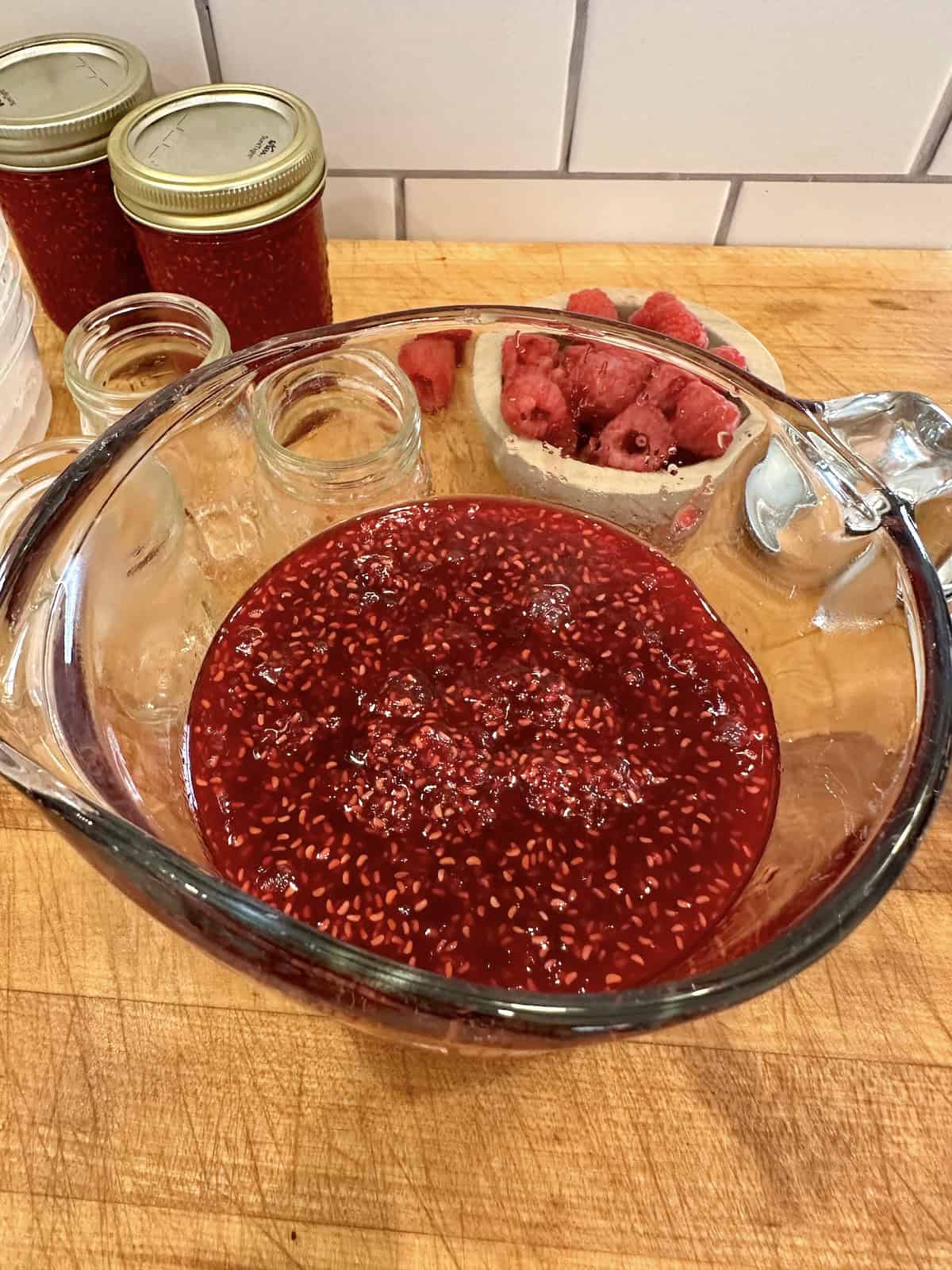 Small batch raspberry jam in a glass measuring cup.