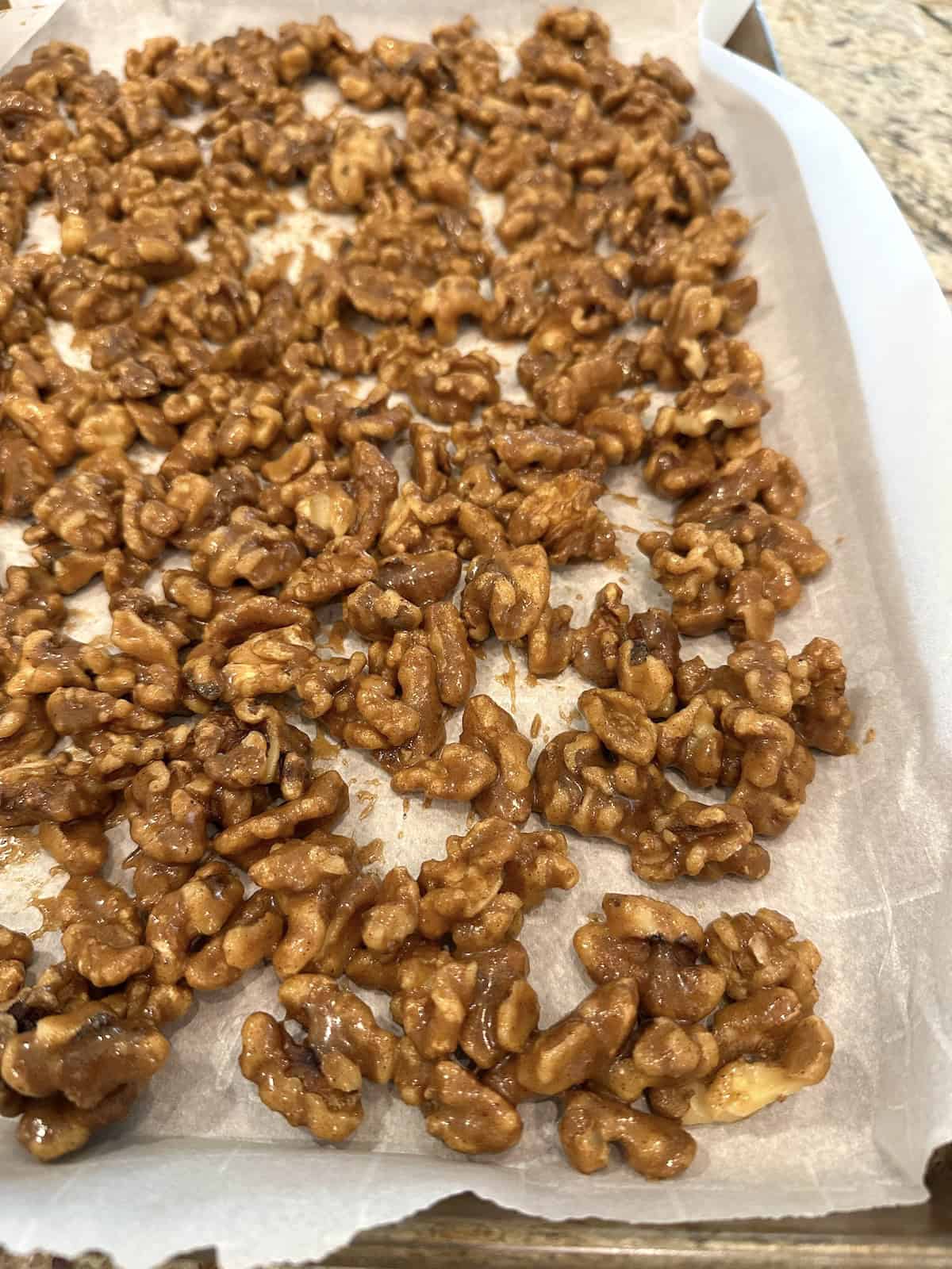 Close-up of spiced walnuts unbaked, coated in spices and syrup.