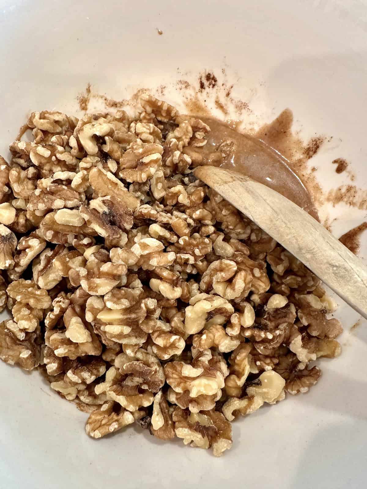 Walnuts in the spices and syrup in a bowl.