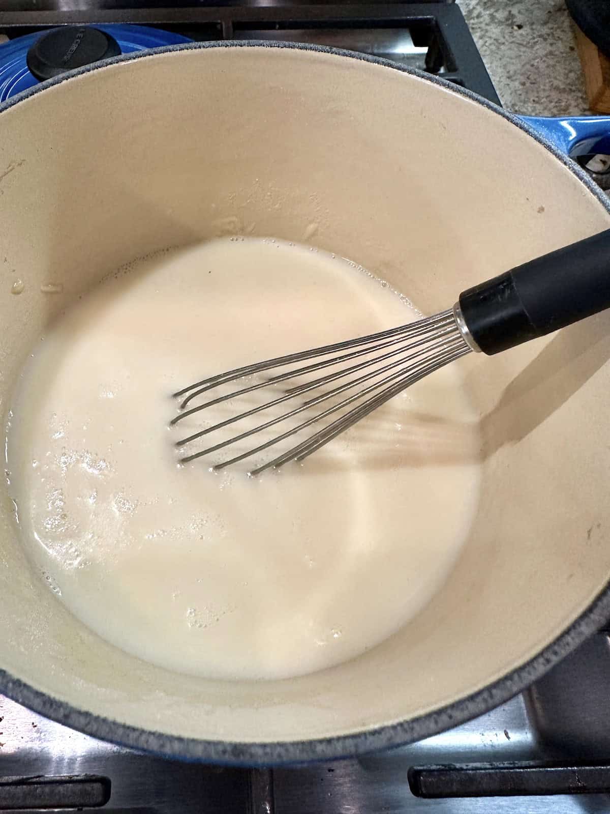 White clam sauce in a pan with a whisk.