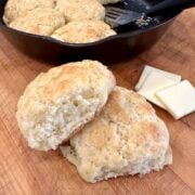 Baked homemade biscuits on a cutting board with butter.