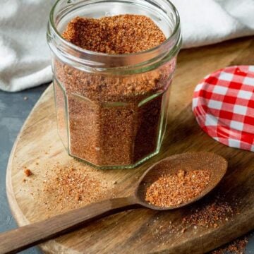 A jar of spice mix on a cutting board.