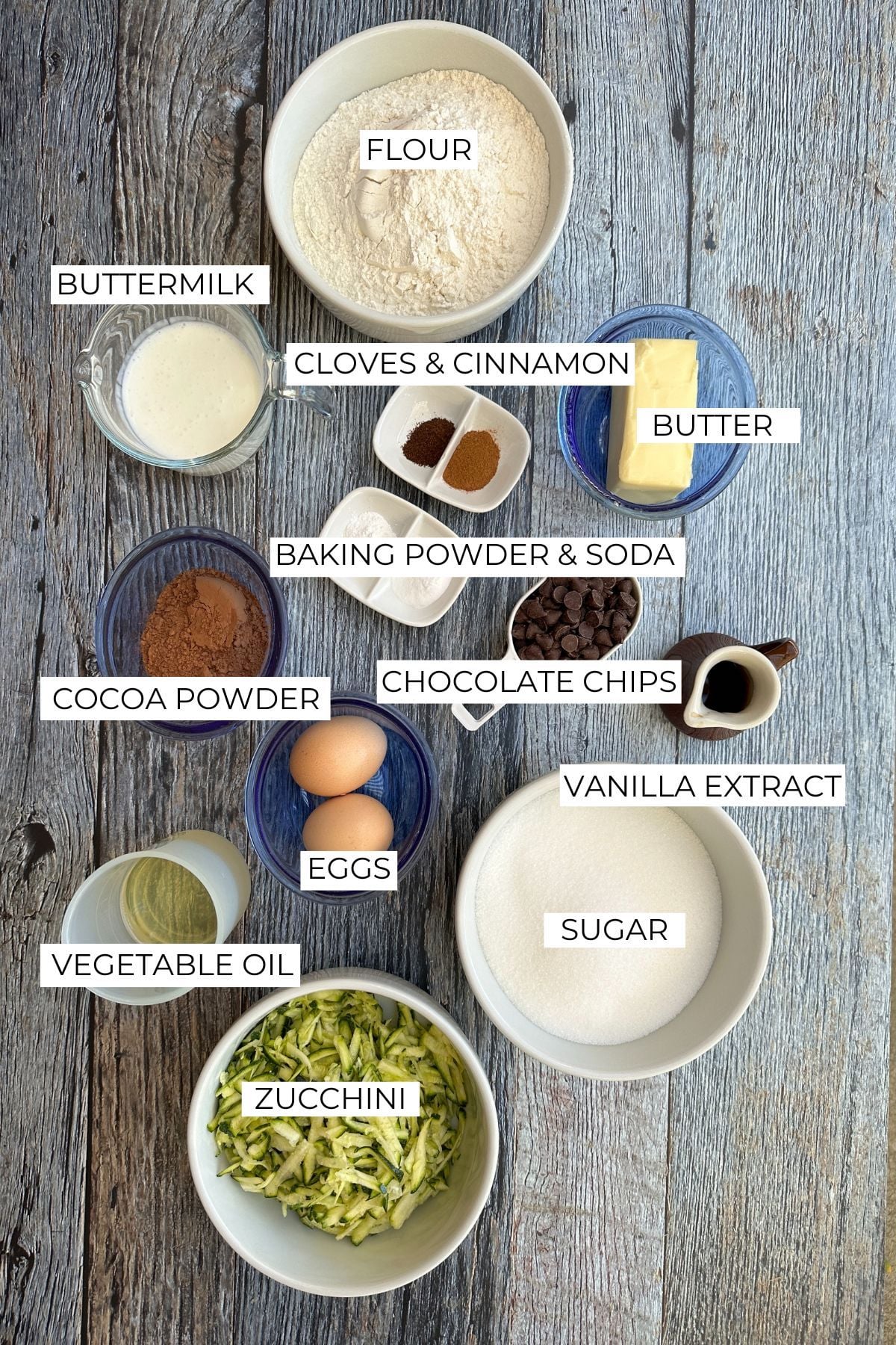 Ingredients for chocolate zucchini cake on a wooden table.