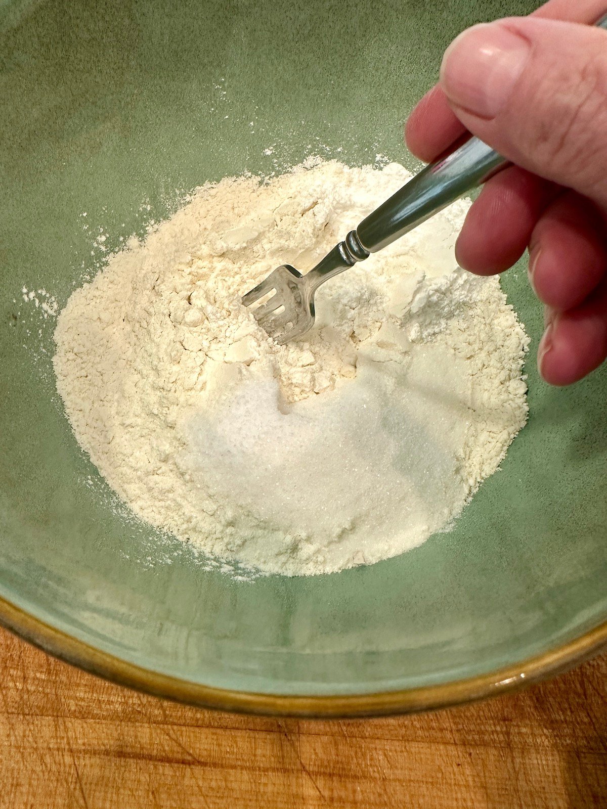 Dry ingredients for homemade biscuits in a bowl with a fork.