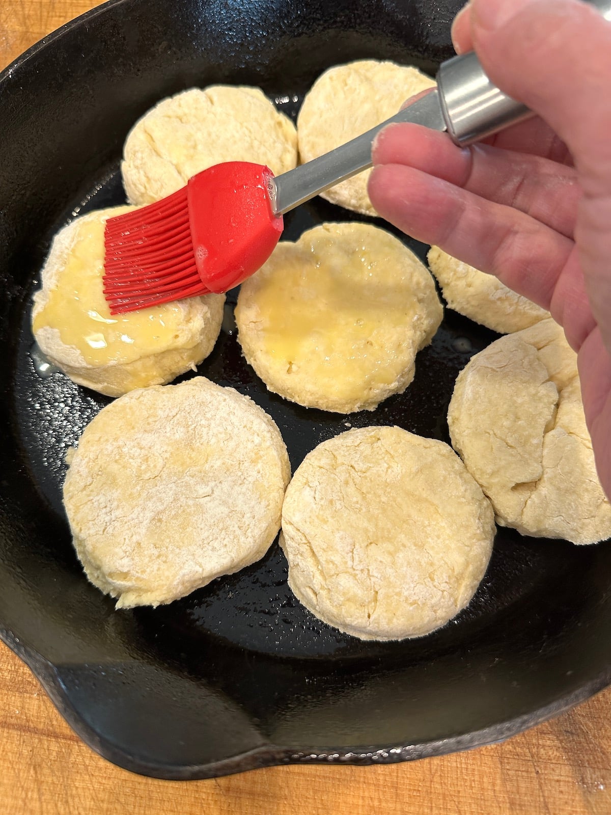 Unbaked biscuits in a cast iron skillet with an egg wash.