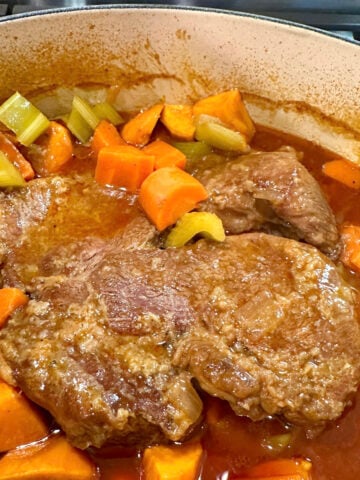 A Dutch oven of tender pot roast with vegetables.