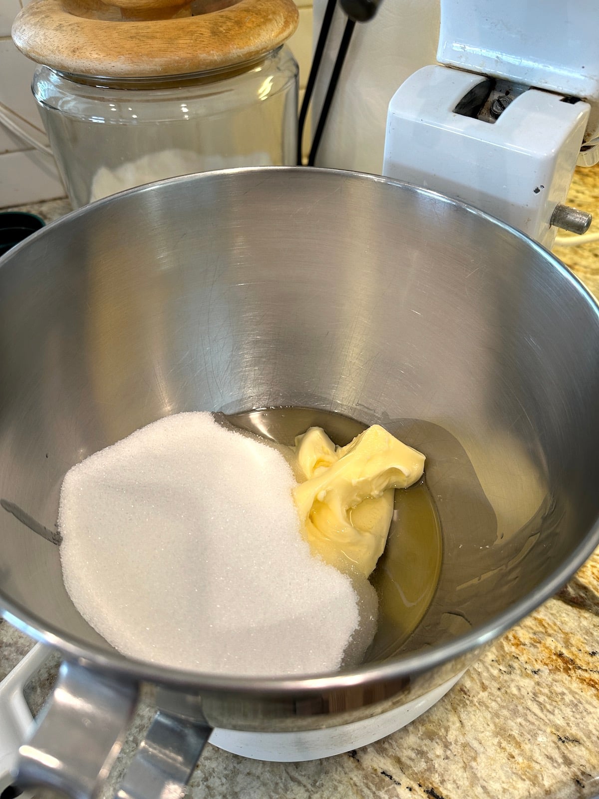 Sugar and vegetable oil with butter in a mixing bowl.
