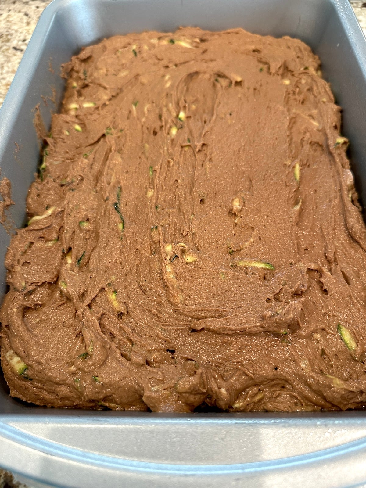 Moist chocolate zucchini cake batter in a baking dish.