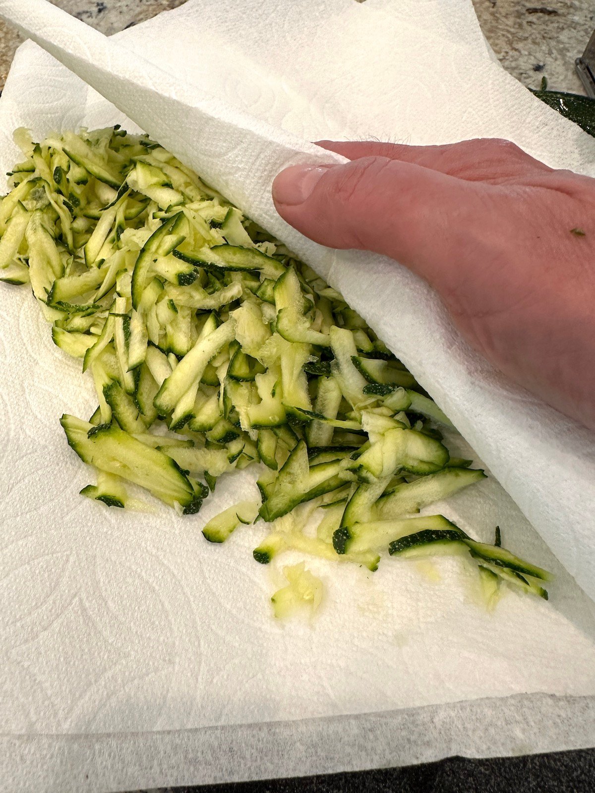 Grated zucchini between two layers of paper towels.