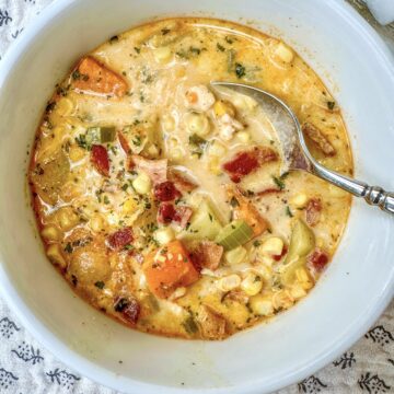 Corn and potato soup with bacon and chicken in a serving bowl.