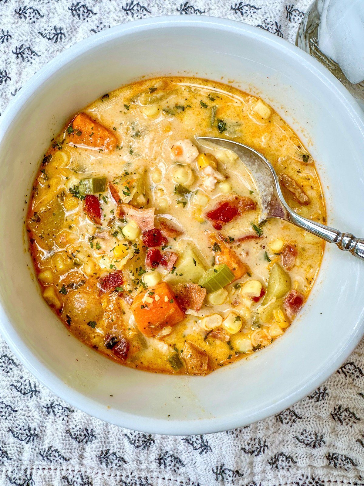 Corn and potato soup with bacon and chicken in a serving bowl.
