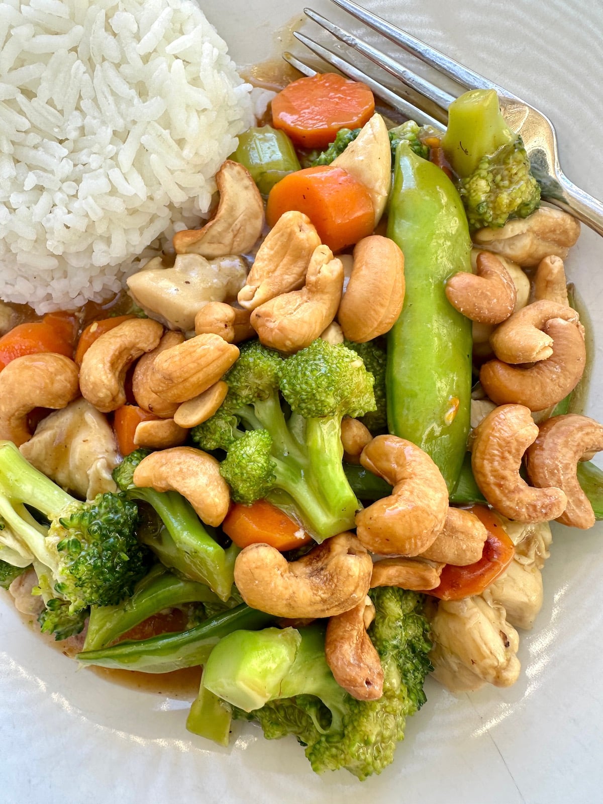 Chicken stir fry with cashews on a plate with rice.
