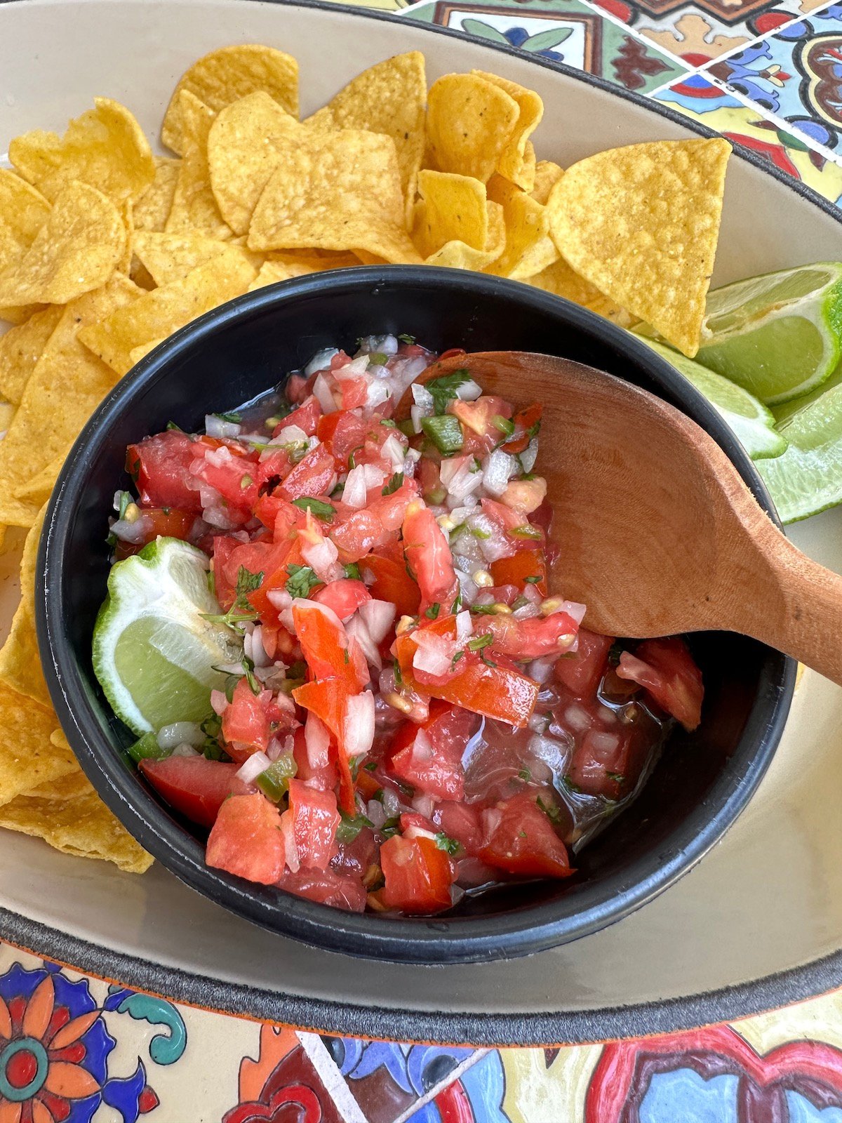 Homemade pico de gallo in a bowl with chips and lime.