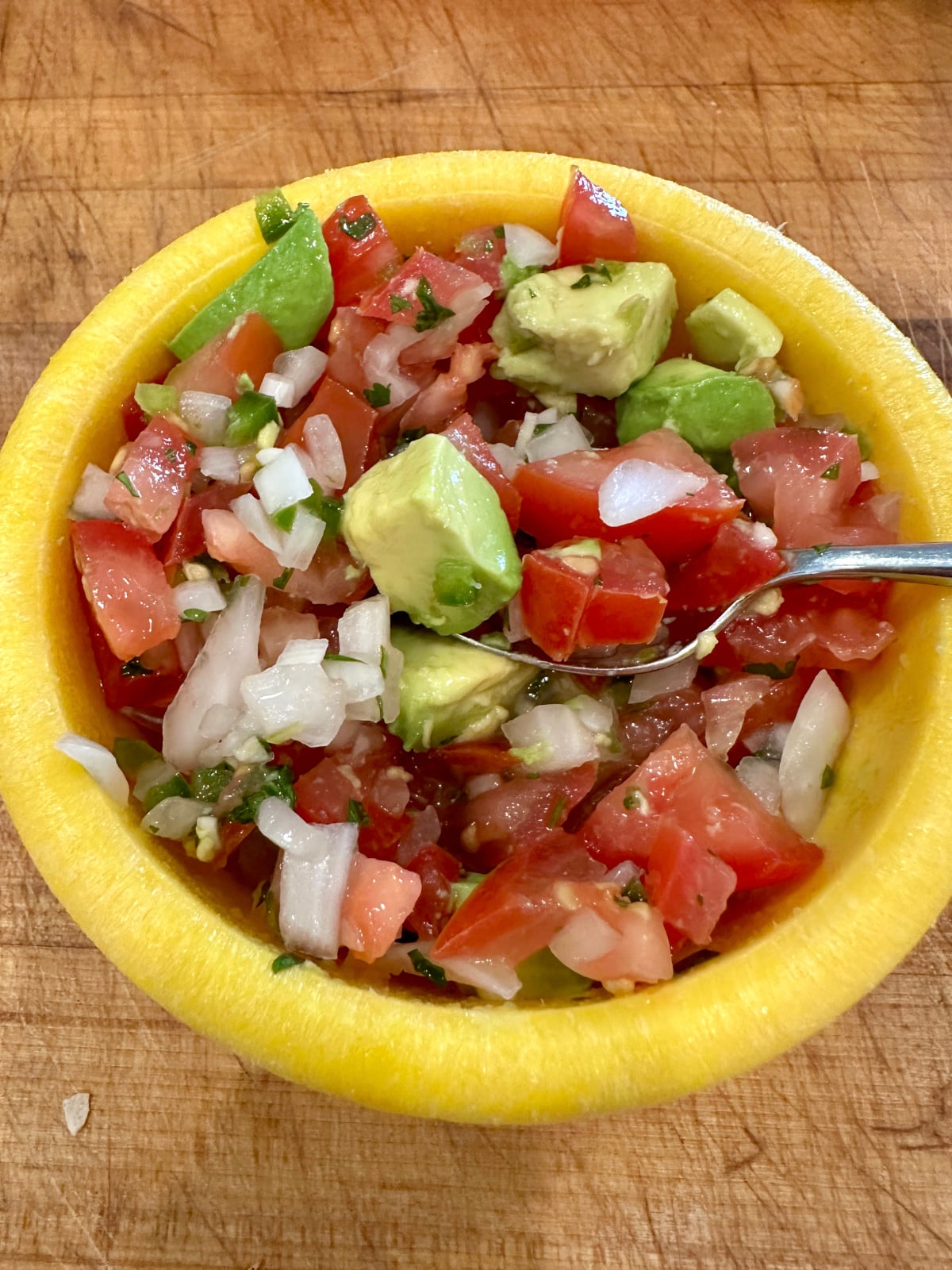 A small bowl of pico de gallo with avocado.