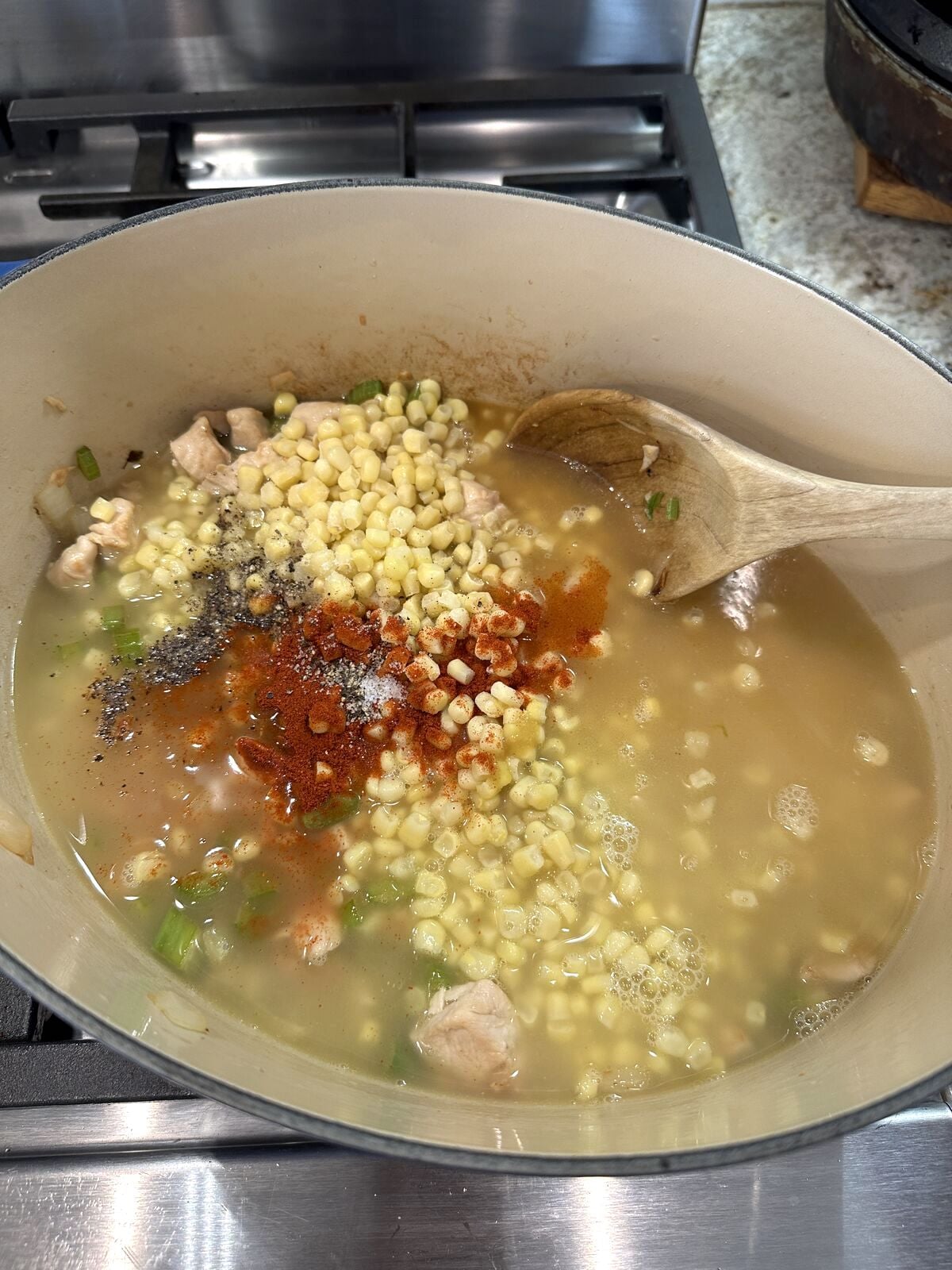 Corn in liquid ingredients and spices in a pan.