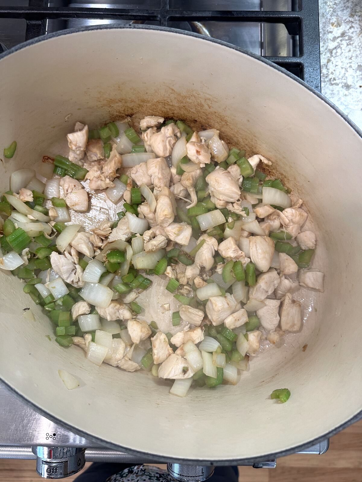 Chicken, celery and onions in a pan on the stove.