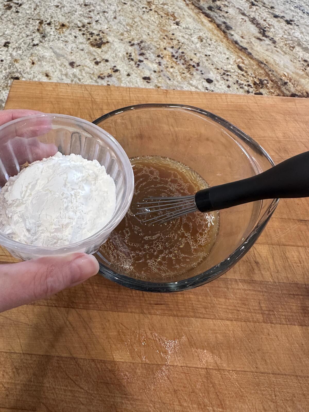 Cornstarch added to sauce in a measuring cup.