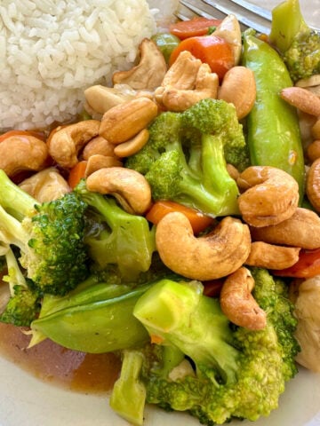A serving of cashew chicken stir fry with sauce and rice.