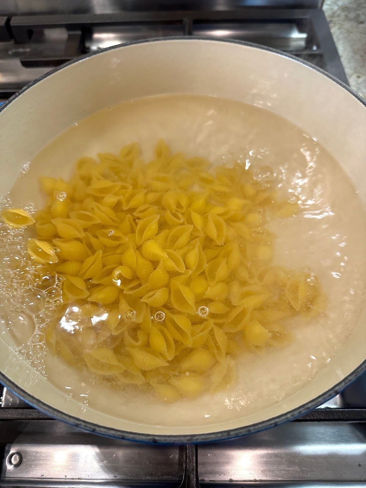Pasta for salad in water in a pot on the stove.