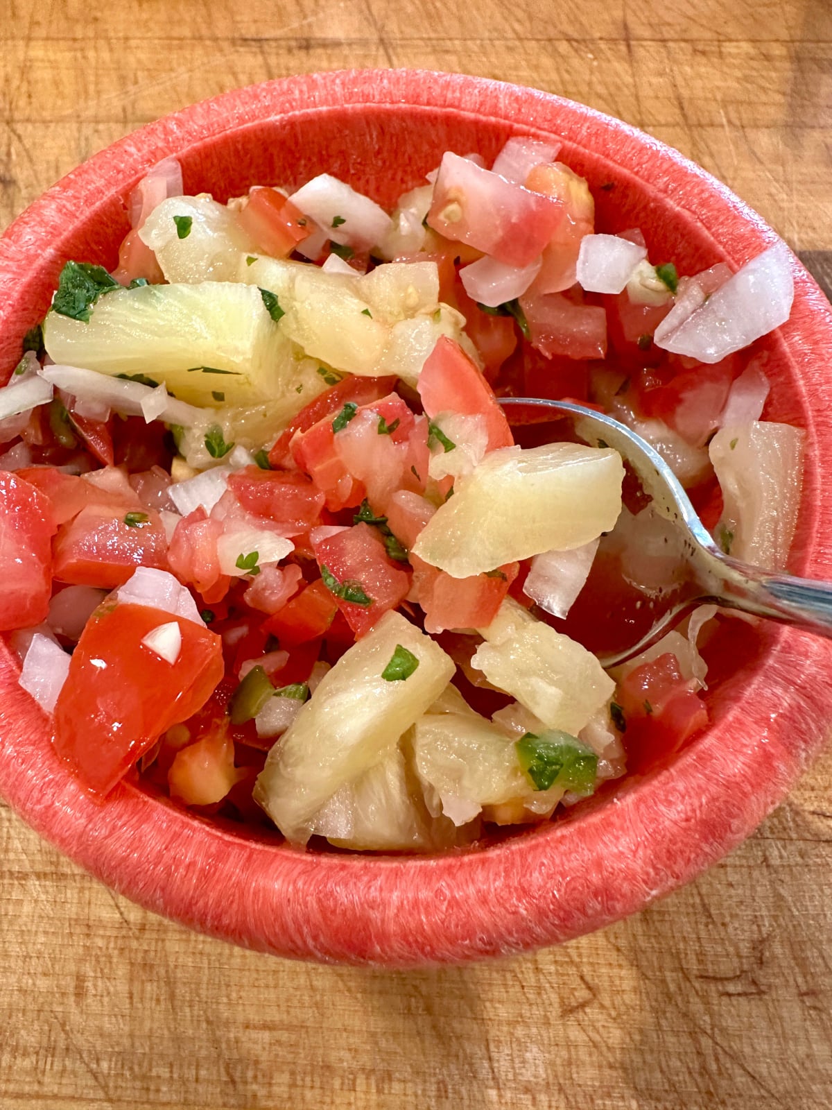A bowl of pico de gallo with pineapple chunks.