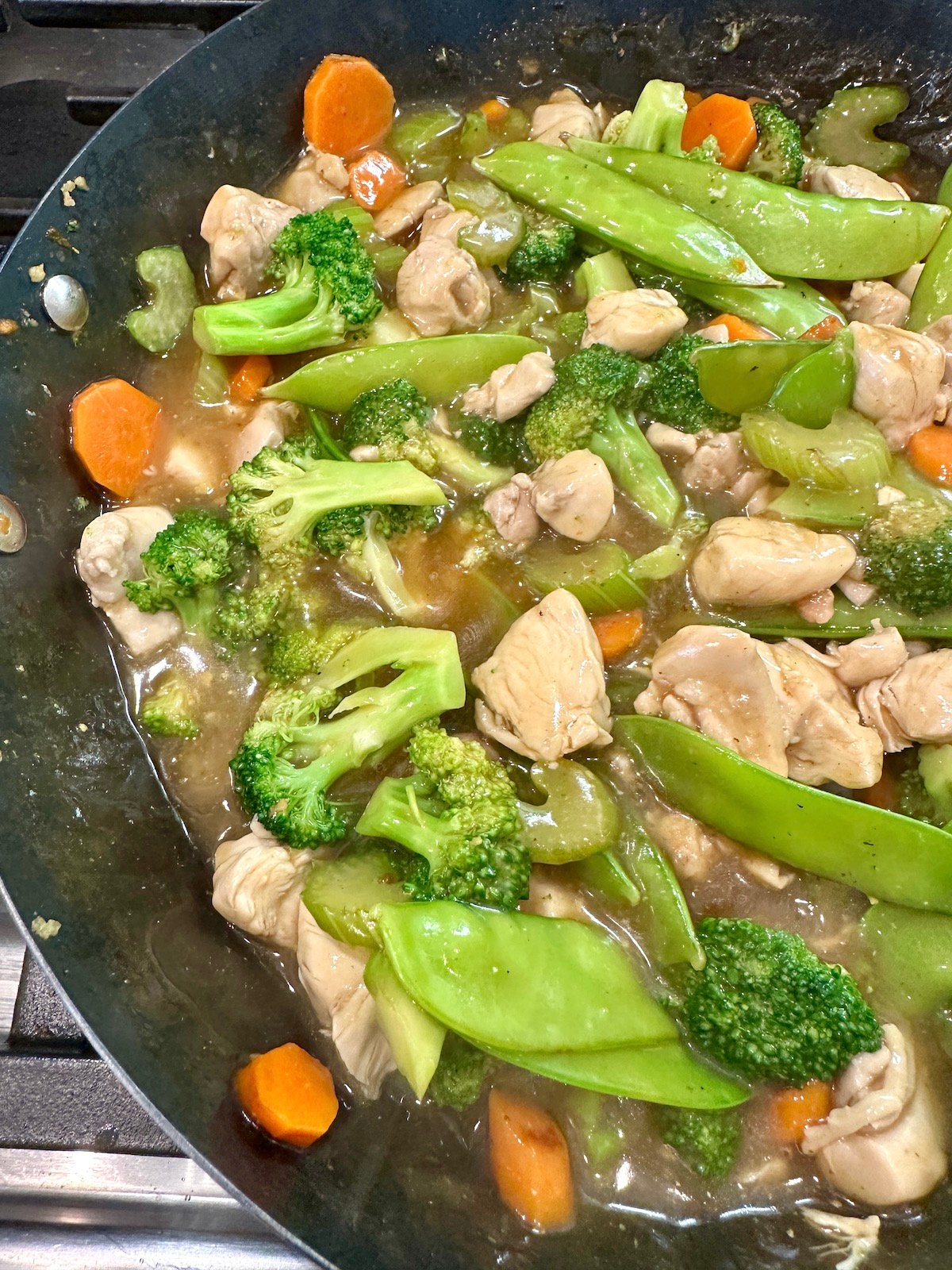 Veggies for cashew chicken stir fry with chicken in a pan.